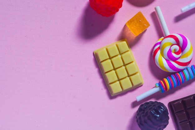 Plat de bonbons sucrés préférés des petits enfants Sucettes colorées bonbons chocolats fond rose