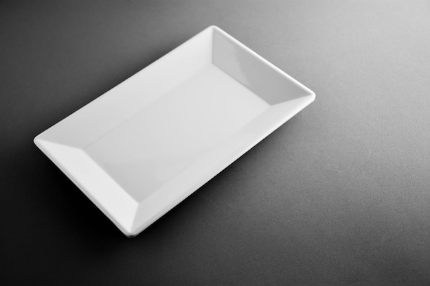 Plat carré en plastique blanc sur un bureau noir