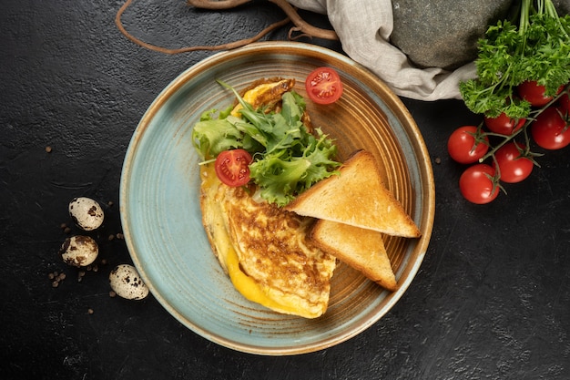 Un plat chaud pour le petit déjeuner avec omelette, salade de fromage et légumes.