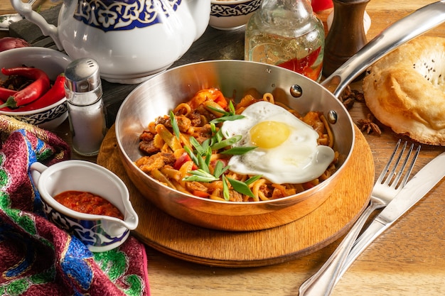 Plat chaud traditionnel ouzbek Fried lagman. Nouilles sautées à l'agneau, légumes, œuf et adjika.