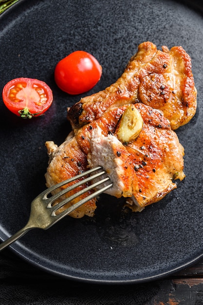 Plat de côtelette de porc grillée avec tomates vue de dessus avec couteau et tranche sur fourchette