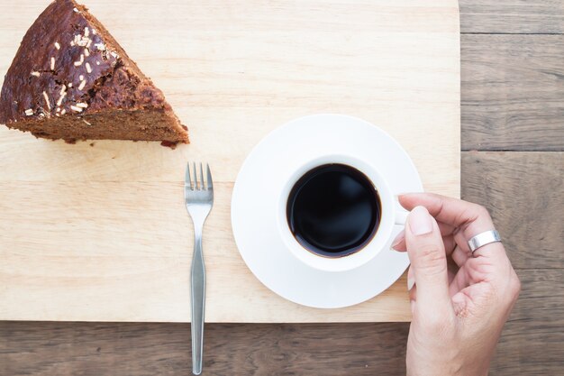 Plat créatif pose de main de femme avec un gâteau au chocolat et au café