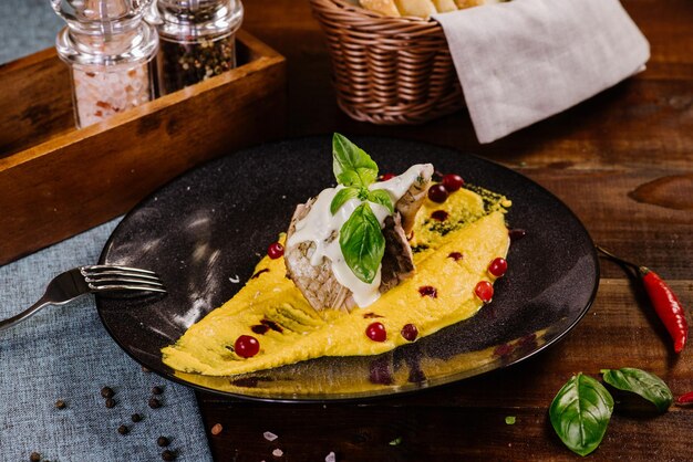 Un plat avec du poisson blanc et de la sauce jaune sur le fond en bois