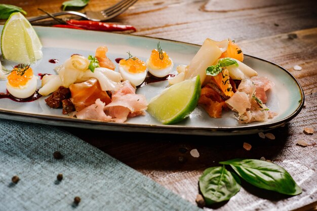 Un plat avec du poisson rouge, blanc, du caviar et des légumes sur le fond en bois