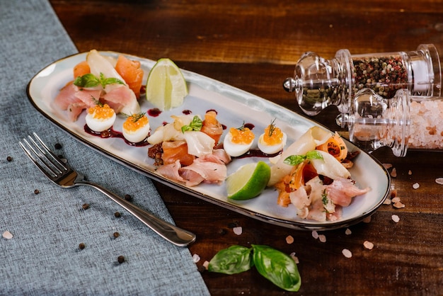 Un plat avec du poisson rouge, blanc, du caviar et des légumes sur le fond en bois