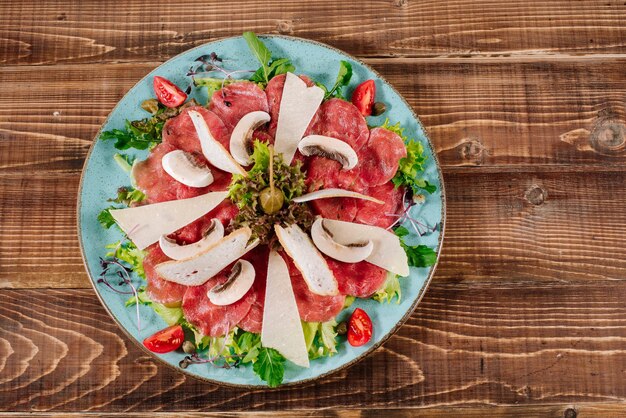 Un plat avec du poisson rouge, du fromage et des champignons sur fond de bois