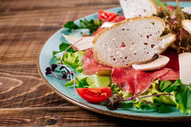 Un plat avec du poisson rouge, du fromage et des champignons sur fond de bois