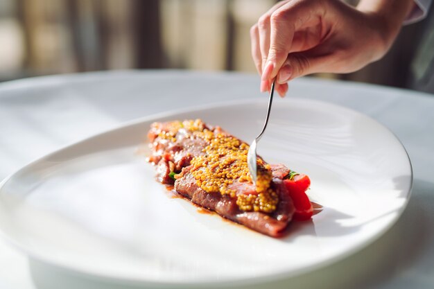 Le plat est le carpaccio. Plat de moutarde granuleuse de bouse de chef, Carpaccio.