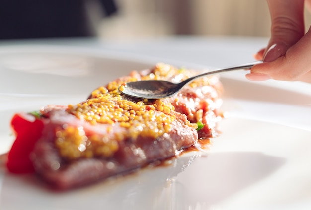 Le plat est le carpaccio. Plat de moutarde granuleuse de bouse de chef, Carpaccio.