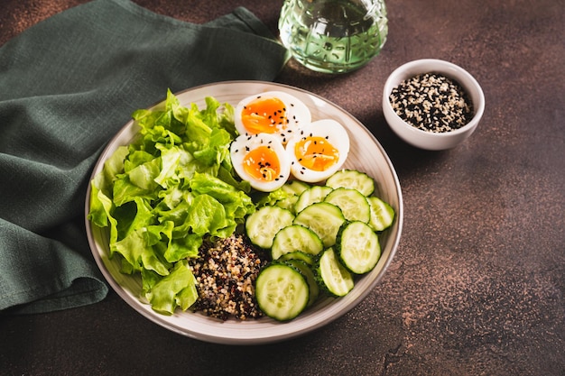 Un plat de fitness avec du quinoa, des œufs de concombre et de la laitue sur la table