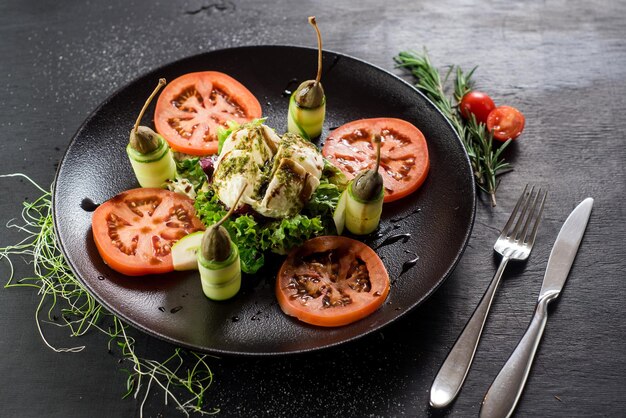 Un plat de fromage de chèvre et de légumes sur fond noir