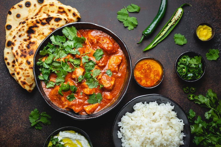 Photo plat indien traditionnel poulet tikka masala avec viande de curry épicé dans un bol, riz basmati, pain naan, sauce raita au yaourt sur fond sombre rustique, vue de dessus, gros plan. dîner de style indien d'en haut