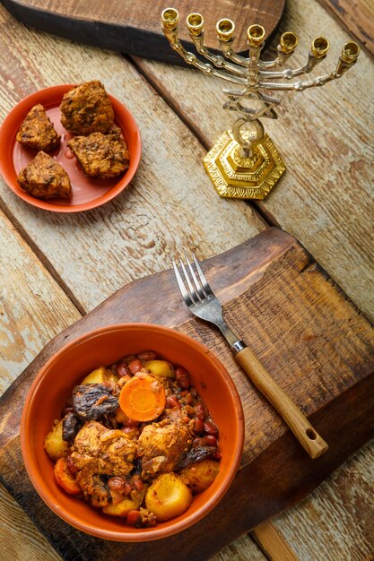 Plat juif fermé avec de la viande sur une table en bois près du pain azyme et des ingrédients. Photo verticale