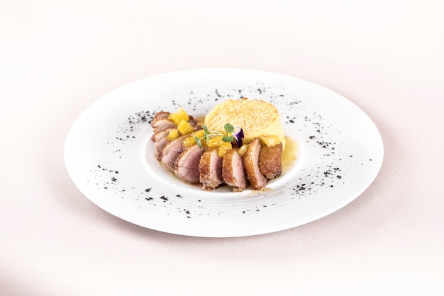 Plat luxueux avec des tranches de magret de canard, des morceaux d&#39;ananas, une sauce sucrée, une purée de pommes de terre