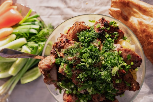 Un plat avec des morceaux de viande de kebab décorés d'herbes