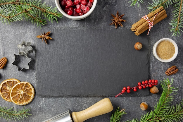 Plat de Noël avec des épices d'hiver et des ingrédients pour la cuisson sur fond sombre.