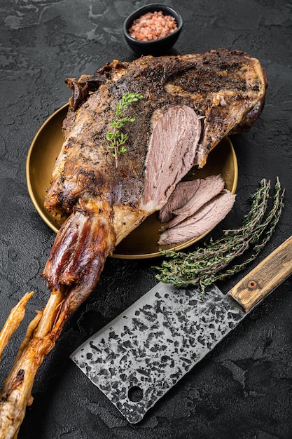 Plat de Noël Viande de gigot d'agneau rôti aux épices et au thym sur une assiette Fond noir Vue de dessus