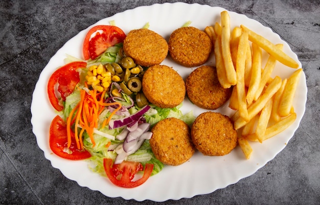 Plat ovale de pommes de terre falafel traditionnelles avec frites et salade