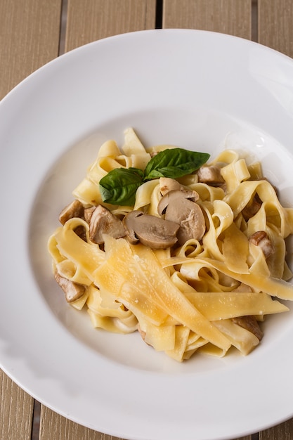 Plat de pâtes végétarien aux tagliatelles aux champignons décoré de basilic.