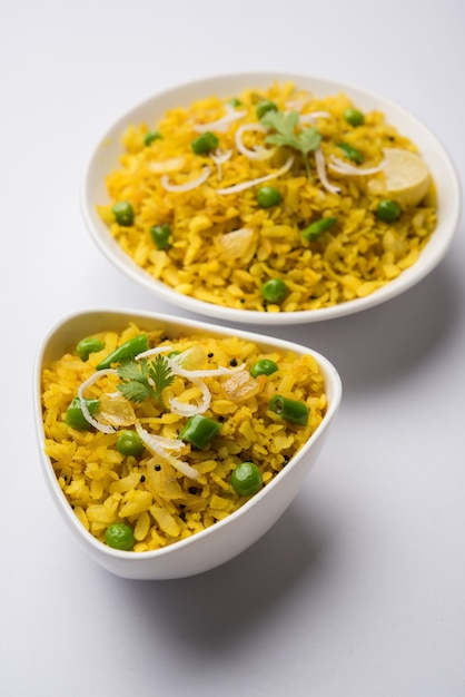 Plat de petit-déjeuner indien Poha également connu sous le nom de Pohe ou Aalu poha composé de riz battu ou de riz aplati. Les flocons de riz sont légèrement frits dans de l'huile avec des épices servis avec du thé chaud