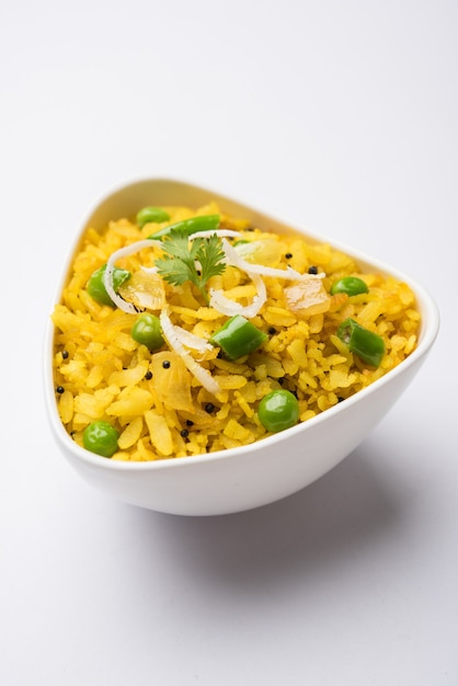 Plat de petit-déjeuner indien Poha également connu sous le nom de Pohe ou Aalu poha composé de riz battu ou de riz aplati. Les flocons de riz sont légèrement frits dans de l'huile avec des épices servis avec du thé chaud