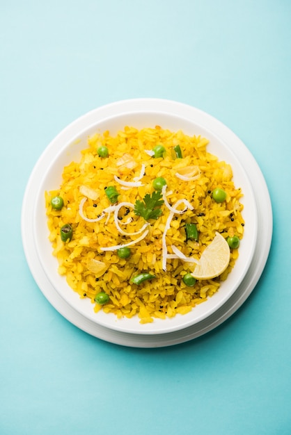 Plat de petit-déjeuner indien Poha également connu sous le nom de Pohe ou Aalu poha composé de riz battu ou de riz aplati. Les flocons de riz sont légèrement frits dans de l'huile avec des épices servis avec du thé chaud