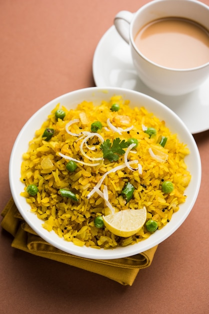 Plat de petit-déjeuner indien Poha également connu sous le nom de Pohe ou Aalu poha composé de riz battu ou de riz aplati. Les flocons de riz sont légèrement frits dans de l'huile avec des épices servis avec du thé chaud