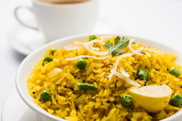 Plat de petit-déjeuner indien Poha également connu sous le nom de Pohe ou Aalu poha composé de riz battu ou de riz aplati. Les flocons de riz sont légèrement frits dans de l'huile avec des épices servis avec du thé chaud