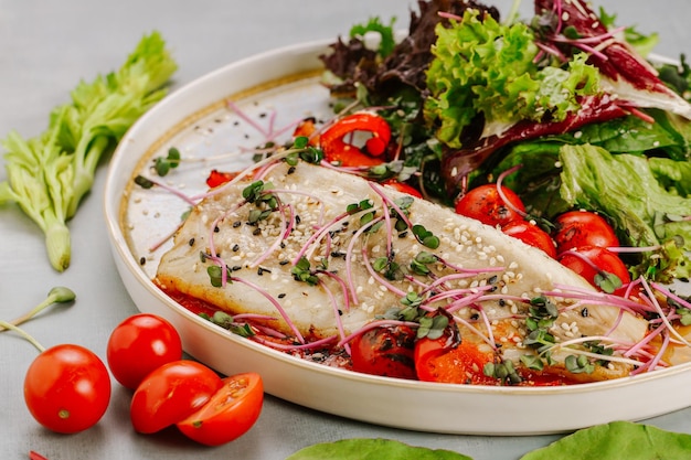 Plat de poisson blanc aux tomates cerises laitue micro-pousses et graines de sésame