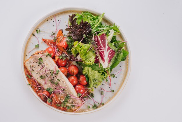 Plat de poisson blanc aux tomates cerises laitue micro-pousses et graines de sésame