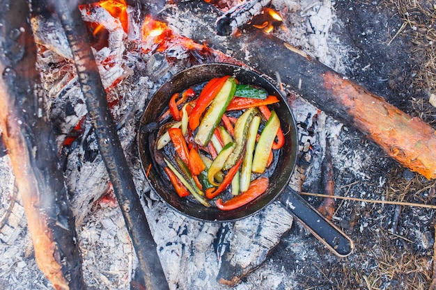 Un plat de poivrons rouges et de concombres dans une casserole sur un feu