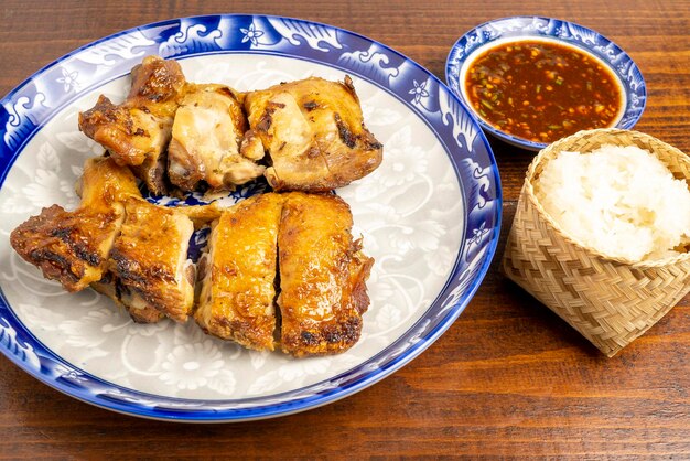 Un plat de poulet grillé coupé en morceaux mariné aux herbes servi avec du riz gluant