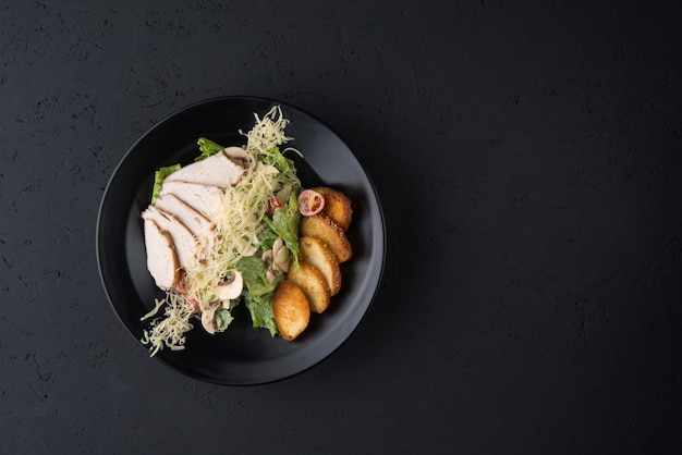 Un plat de poulet sur la surface en bois noir, vue de dessus