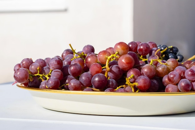 Un plat avec des raisins délicieux sur une table dehors par une journée ensoleillée