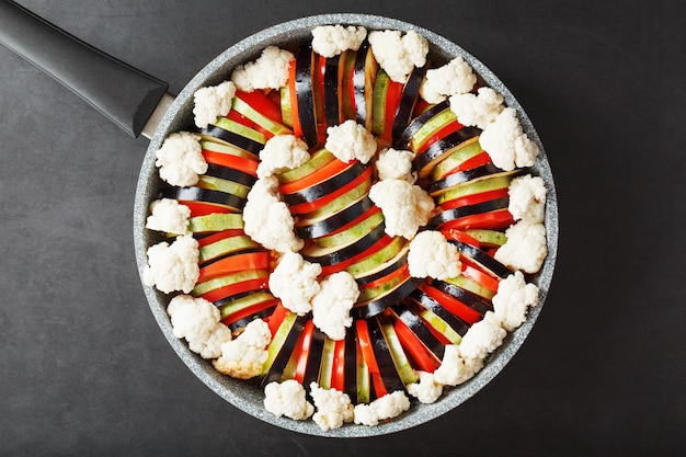 Plat de ratatouille de légumes frais dans une poêle à frire sur fond sombre.