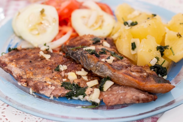 Plat de repas portugais de poisson de ventre de thon grillé avec pommes de terre et salade de tomates.