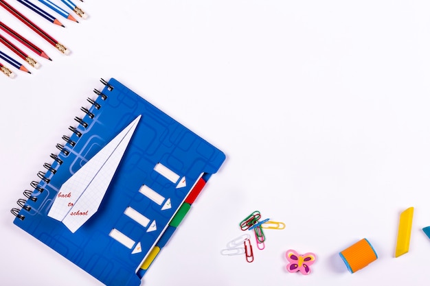 plat retour à l'école. Cahier d'école, un avion de papier et accessoires