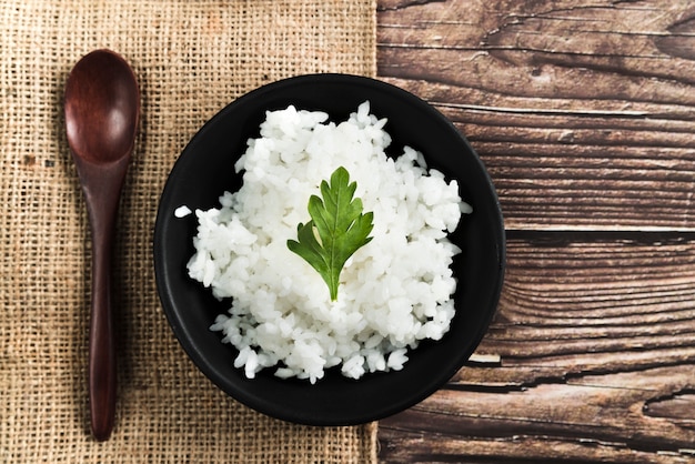 Plat de riz avec du persil près de la cuillère en bois et un sac