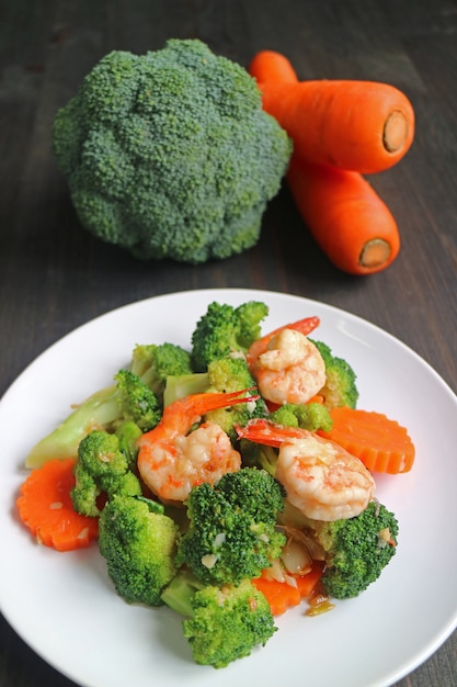 Plat sain de crevettes sautées au brocoli et aux carottes servi sur une plaque blanche