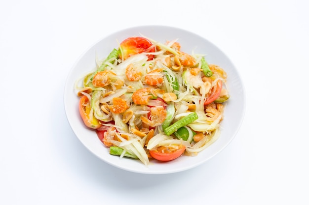 Plat de salade de papaye épicée sur tableau blanc.