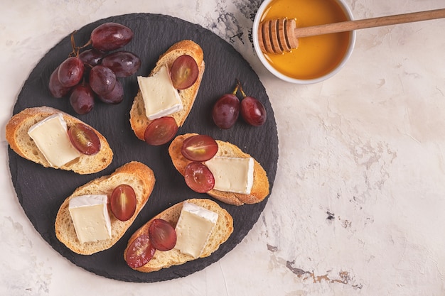 Plat avec des sandwichs au fromage, raisins et miel