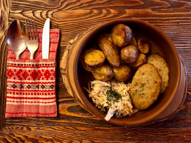 Plat slave traditionnel pommes de terre au four avec escalopes en terre cuite et salade sur table en bois. Dîner