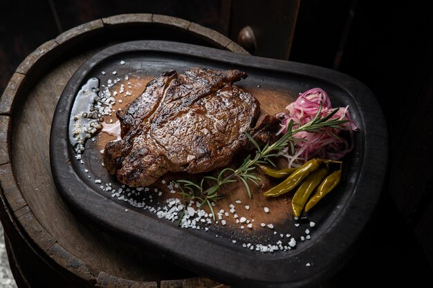 Un plat de steak avec des oignons rouges et des poivrons verts sur une plaque noire.