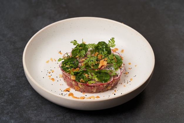 Plat de tartare de boeuf aux légumes frais en plaque blanche