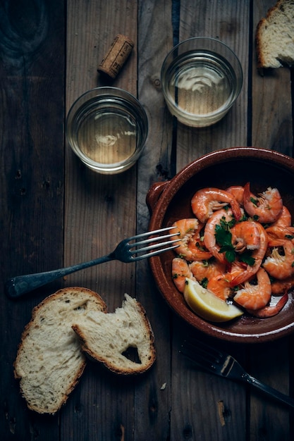 Plat en terre cuite avec crevettes à l'ail p et deux verres de vin