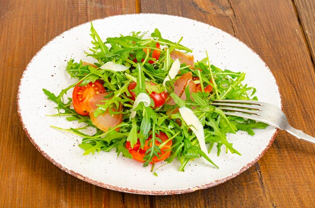 Plat de tomates roquette viande séchée et salade de fromage sur plaque sur bois