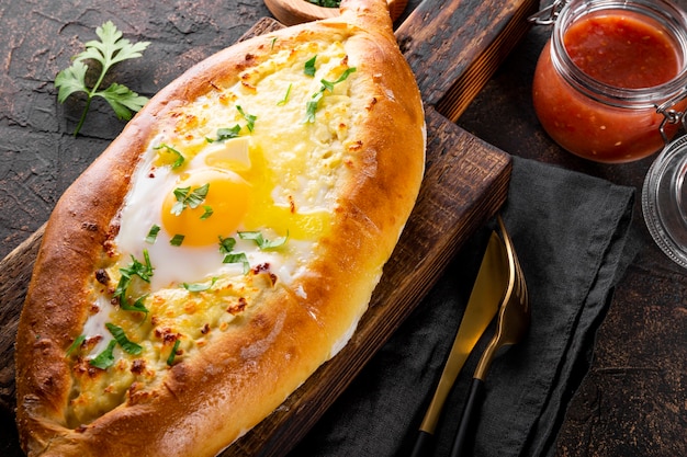 un plat traditionnel de la cuisine géorgienne khachapuri adjare avec fromage et œuf et tomate épicée