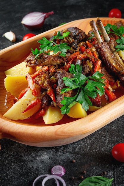 Photo plat traditionnel kazakh kuirdak rôti aromatique de sous-produits de la viande d'agneau avec beaucoup d'oignons et de légumes dans un plat en bois astau