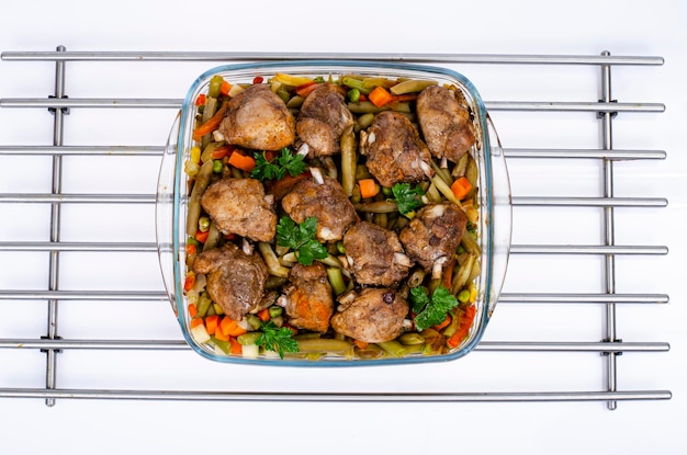 Plat en verre avec légumes cuits au four et morceaux de poulet. Studio photo