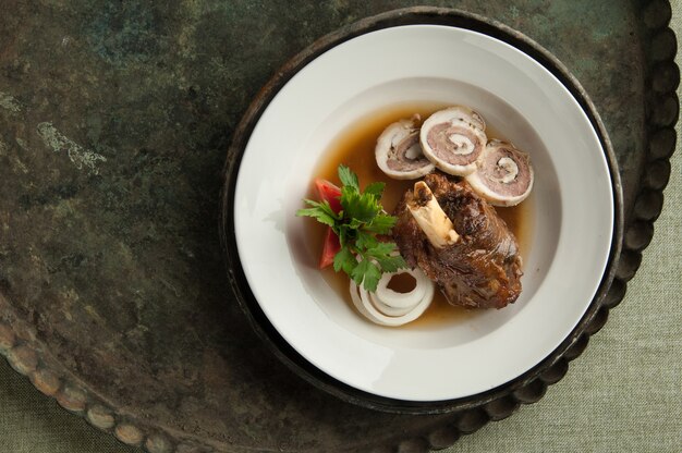 Un plat de viande avec un os sur un vieux plateau antique